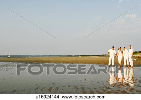Picture - Mature couple standing with a mid adult woman and a mature man on the beach. Fotosearch