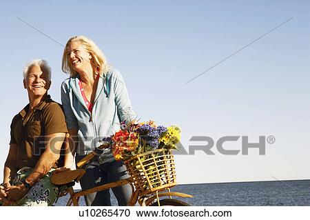 Mature couple with a bicycle on the beach View Large Photo Image Stock Image - Mature couple with a bicycle on the beach. Fotosearch