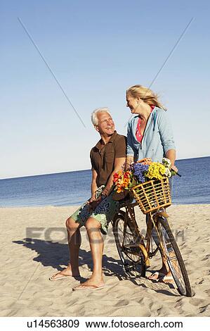 Mature couple with a bicycle on the beach View Large Photo Image Stock Photo - Mature couple with a bicycle on the beach. Fotosearch