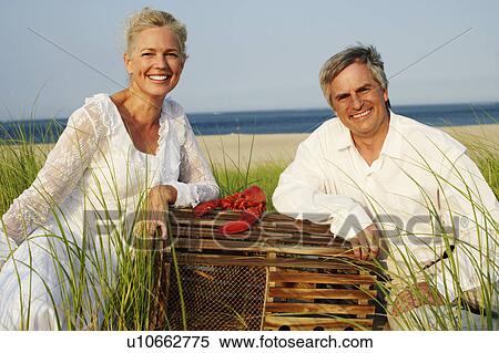Portrait of a mature couple sitting on the beach with a lobster View Large Photo Image Stock Photography - Portrait of a mature couple sitting on the beach with a lobster. Fotosearch