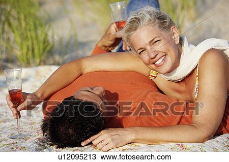 Portrait of a mature woman lying on the beach with a mature man View Large Photo Image Stock Image - Portrait of a mature woman lying on the beach with a mature man. Fotosearch