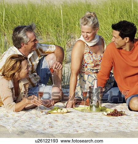 Two mature couples sitting on the beach and holding champagne flutes View Large Photo Image Stock Image - Two mature couples sitting on the beach and holding champagne flutes. Fotosearch