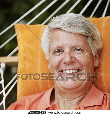 Stock Photo - Portrait of a mature man lying in a hammock and smiling. Fotosearch