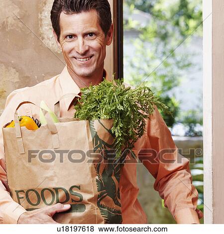 Stock Photo - Portrait of a mature man smiling and holding a shopping bag. Fotosearch