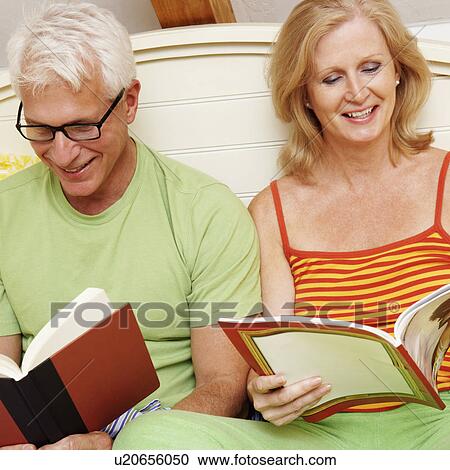 Close-up of a mature couple sitting on the bed and reading books View Large Photo Image Stock Image - Close-up of a mature couple sitting on the bed and reading books. Fotosearch