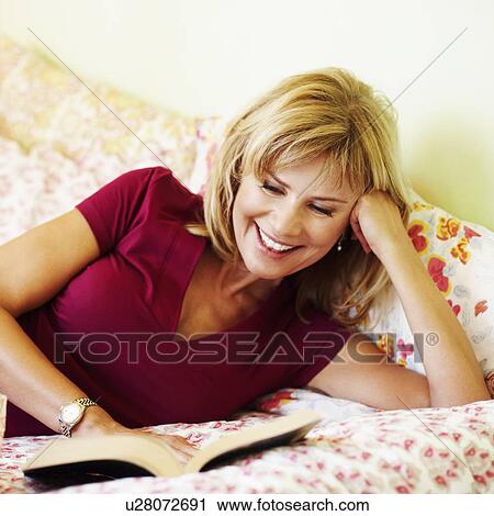 Close-up of a mature woman lying on the bed reading a book View Large Photo Image Stock Image - Close-up of a mature woman lying on the bed reading a book. Fotosearch