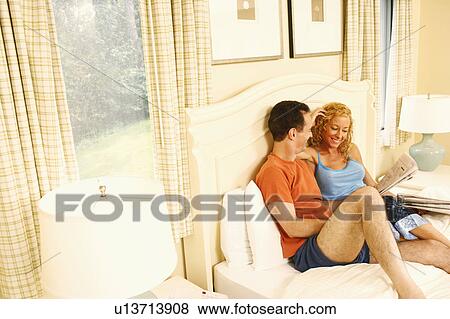 High angle view of a mature couple sitting on the bed and holding a newspaper View Large Photo Image Stock Photo - High angle view of a mature couple sitting on the bed and holding a newspaper. Fotosearch