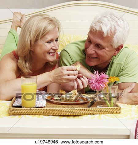 Mature couple having breakfast in bed View Large Photo Image Stock Photograph - Mature couple having breakfast in bed. Fotosearch