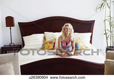 Mid adult woman sitting on the bed with a bowl full of grapes and smiling View Large Photo Image Picture - Mid adult woman sitting on the bed with a bowl full of grapes and smiling. Fotosearch