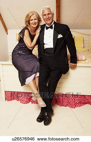 Portrait of a mature couple sitting on the bed and smiling View Large Photo Image Stock Photograph - Portrait of a mature couple sitting on the bed and smiling. Fotosearch