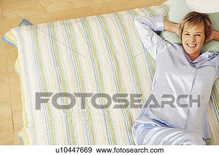 Stock Photo - Portrait of a mature woman lying in bed and smiling. Fotosearch