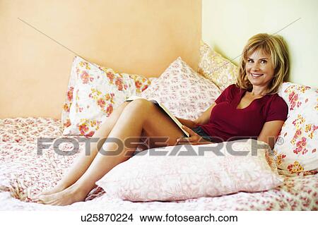 Picture - Portrait of a mature woman reclining on the bed. Fotosearch