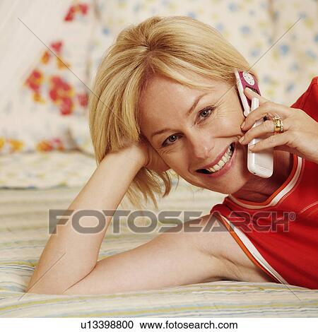 Stock Image - Portrait of a mature woman talking on a flip phone and smiling. Fotosearch