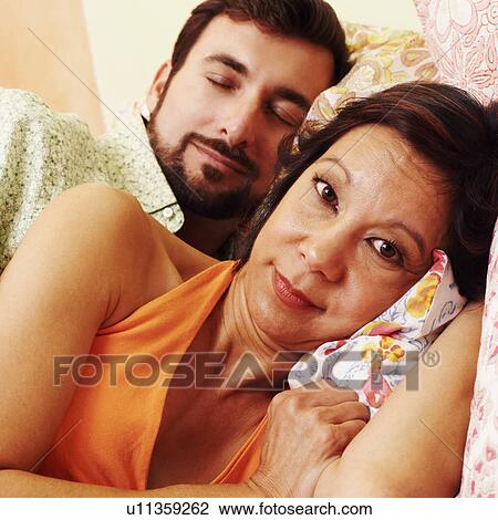 Stock Image - Portrait of a mature woman with a mature man sleeping behind her. Fotosearch