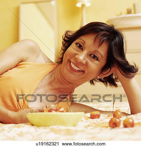 Portrait of a young woman lying on the bed and smiling View Large Photo Image Stock Image - Portrait of a young woman lying on the bed and smiling. Fotosearch