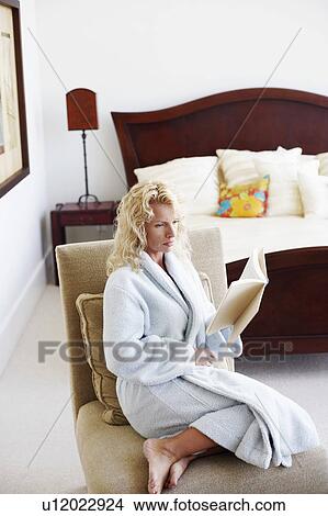 Side profile of a mid adult woman sitting on a chair and reading a book View Large Photo Image Picture - Side profile of a mid adult woman sitting on a chair and reading a book. Fotosearch
