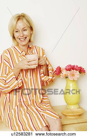 Close-up of a mature woman holding a cup and smiling View Large Photo Image Stock Image - Close-up of a mature woman holding a cup and smiling. Fotosearch
