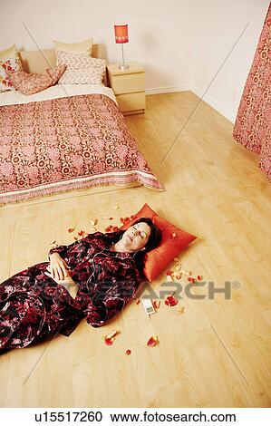High angle view of a mature woman lying on a wooden floor and listening to an MP3 player View Large Photo Image Stock Image - High angle view of a mature woman lying on a wooden floor and listening to an MP3 player. Fotosearch