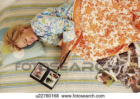 High angle view of a mature woman lying in bed and looking at a photo album View Large Photo Image Stock Photo - High angle view of a mature woman lying in bed and looking at a photo album. Fotosearch