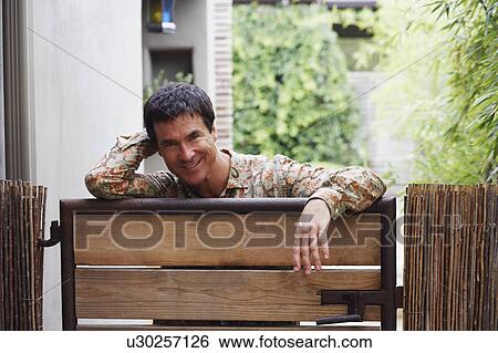 Portrait of a mature man leaning on a gate View Large Photo Image Stock Photograph - Portrait of a mature man leaning on a gate. Fotosearch