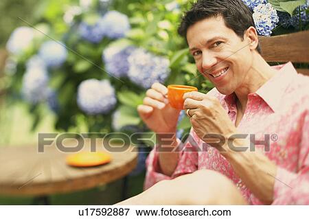 Stock Photo - Portrait of a mature man sitting on a chair and drinking a cup of tea. Fotosearch
