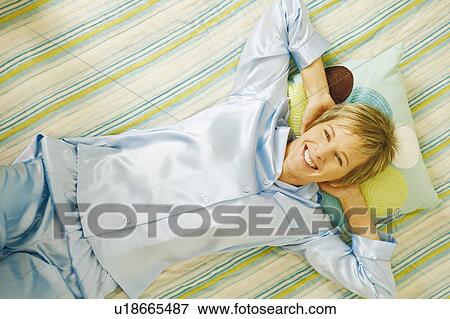 Stock Photo - Portrait of a mature woman lying in bed and smiling. Fotosearch