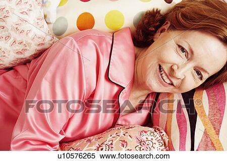 Portrait of a mature woman lying in bed and smiling View Large Photo Image Stock Photography - Portrait of a mature woman lying in bed and smiling. Fotosearch