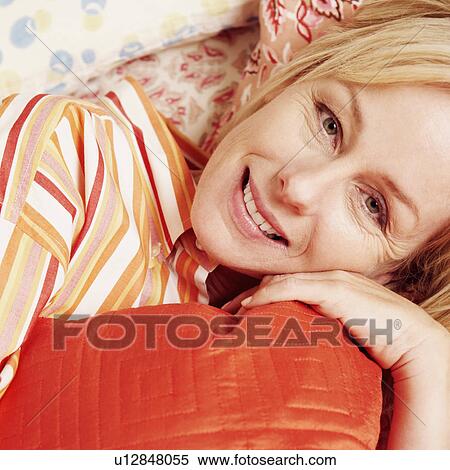 Stock Photography - Portrait of a mature woman lying in bed and smiling. Fotosearch