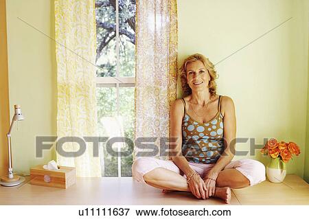 Stock Photo - Portrait of a mature woman sitting and smiling. Fotosearch