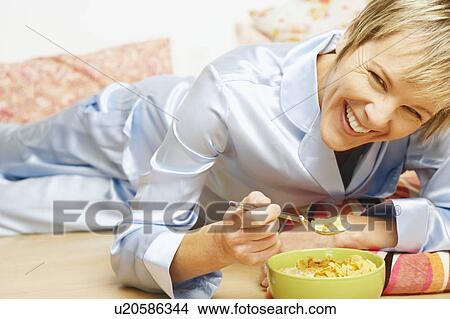 Portrait of a mature woman smiling and eating corn flakes View Large Photo Image Picture - Portrait of a mature woman smiling and eating corn flakes. Fotosearch