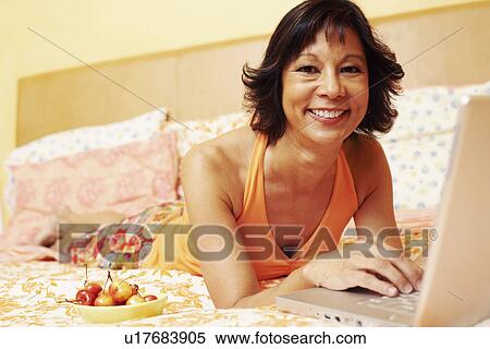 Stock Photography - Portrait of a mature woman smiling and using a laptop. Fotosearch