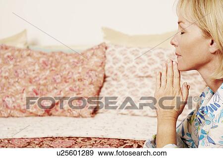 Side profile of a mature woman praying in a bedroom View Large Photo Image Stock Photo - Side profile of a mature woman praying in a bedroom. Fotosearch