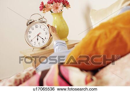 Stock Photograph - Woman's hand reaching for an alarm clock. Fotosearch