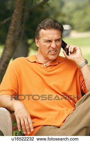 Stock Image - Close-up of a mature man talking on a mobile phone and looking frustrated. Fotosearch