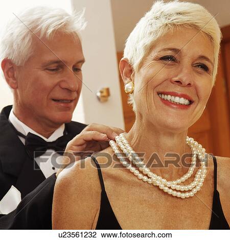 Stock Image - Close-up of a mature man putting a pearl necklace around a mature woman's neck. Fotosearch