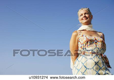Picture - Low angle view of a mature woman looking away and smiling. Fotosearch
