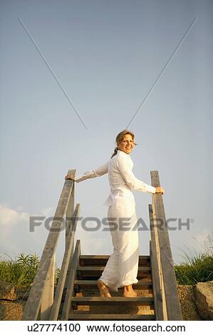 Stock Image - Low angle view of a mature woman standing on a staircase. Fotosearch
