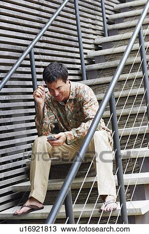 Mature man sitting on a staircase and holding a personal data assistant View Large Photo Image Stock Image - Mature man sitting on a staircase and holding a personal data assistant. Fotosearch
