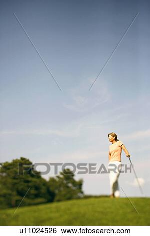 Mature woman standing with a golf club View Large Photo Image Stock Photograph - Mature woman standing with a golf club. Fotosearch