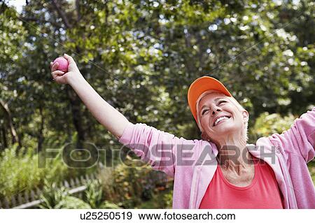 Stock Photo - Mature woman standing with her arms outstretched and smiling. Fotosearch