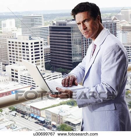 Stock Photo - Portrait of a businessman using a laptop in a balcony. Fotosearch