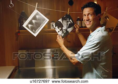 Portrait of a mature man holding photographs in a dark room View Large Photo Image Stock Photo - Portrait of a mature man holding photographs in a dark room. Fotosearch