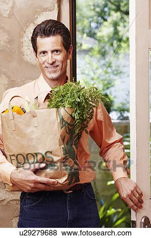 Portrait of a mature man smiling and holding a shopping bag View Large Photo Image Stock Photo - Portrait of a mature man smiling and holding a shopping bag. Fotosearch