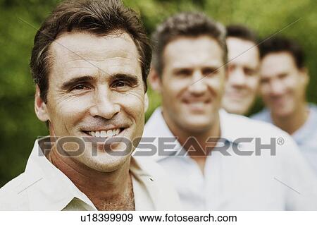 Portrait of a mature man smiling with his friends in the background View Large Photo Image Stock Photo - Portrait of a mature man smiling with his friends in the background. Fotosearch