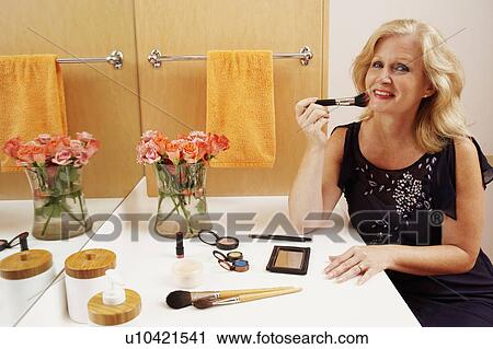 Portrait of a mature woman applying make-up in the bathroom View Large Photo Image Stock Image - Portrait of a mature woman applying make-up in the bathroom. Fotosearch