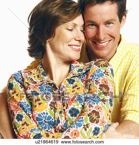 Stock Photo - Portrait of a mid adult man embracing a mid adult woman and smiling. Fotosearch