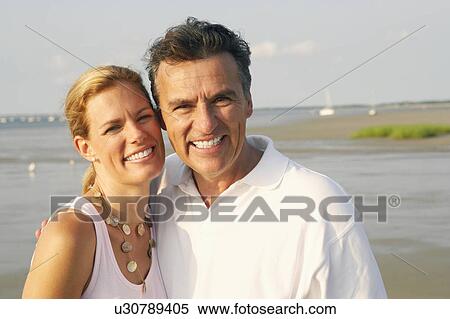 Portrait of a mid adult woman and a mature man standing on the beach and smiling View Large Photo Image Stock Photography - Portrait of a mid adult woman and a mature man standing on the beach and smiling. Fotosearch
