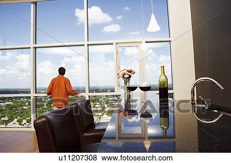 Rear view of a mature man looking through a window View Large Photo Image Stock Photo - Rear view of a mature man looking through a window. Fotosearch