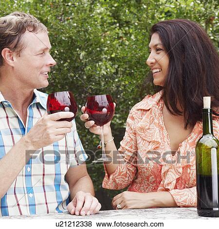 Close-up of a mature couple holding glasses of wine and smiling View Large Photo Image Stock Photo - Close-up of a mature couple holding glasses of wine and smiling. Fotosearch