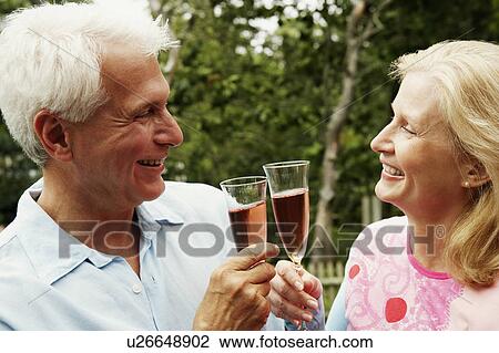 Close-up of a mature couple toasting champagne flutes View Large Photo Image Stock Image - Close-up of a mature couple toasting champagne flutes. Fotosearch